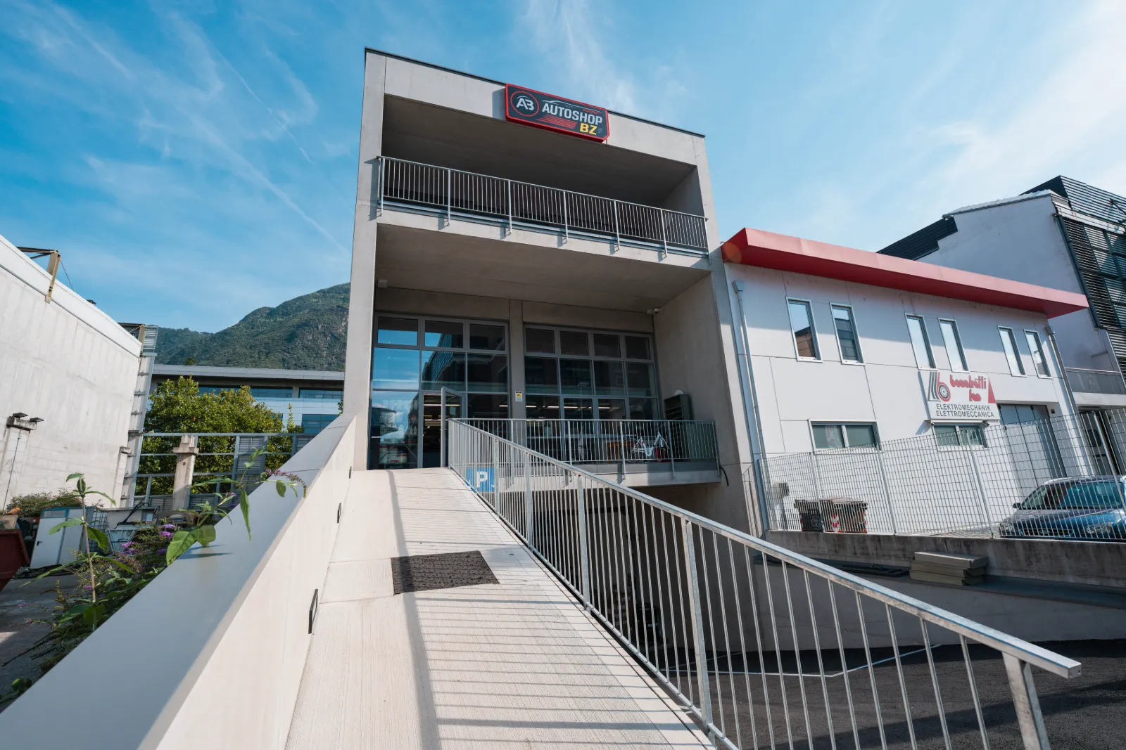 Eingang von Autoshop Bozen mit Bergen im Hintergrund