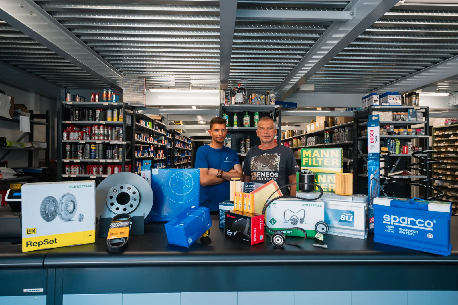 Zwei Mitarbeiter von Autoshop Bozen hinter der Theke mit Ersatzteilen